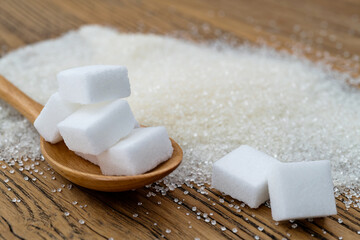 Spoon with sugar cubes on top of granulated sugar