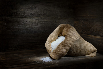 Hessian bag overflowing long grain White Rice rustic wooden box spotlight mood lighting copy space