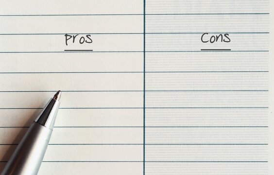 A silver pen on a line note paper with two choices to choose between PROS and  CONS - concept of comparing something to know its advantages and disadvantages to consider and make a sensible decision