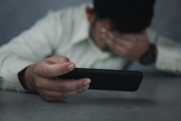 Businessman having a headache after reading from a smartphone. Upset Asian businessman