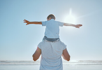 Fototapeta na wymiar Family, beach and summer vacation for freedom with a child on shoulder of father with hands outstretched for happiness against blue sky. Man and kid son together at sea for trust, nature and peace