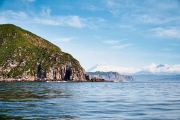 Summer landscape of the coastline with snow covered volcano. Kamchatka