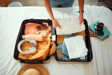 Travel packing, above and hands of a woman with clothes, holiday luggage and prepare for...