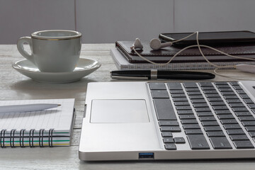 Workplace. A laptop, a cup of coffee and other accessories on a white desktop. Side view