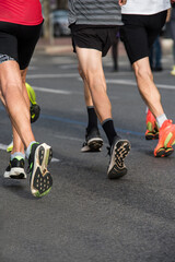 Photo detail of the shoes of three runners advancing towards the finish line. Vertical concept of effort and sports training