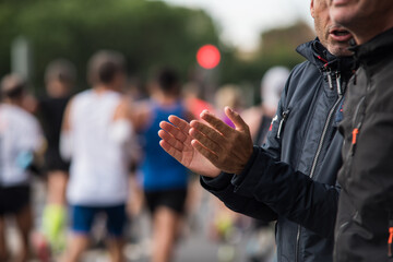 Close-up photo, detail of person applauding and cheering the marathon runners.