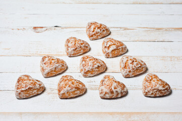 Sweet heart-shaped glazed gingerbread photographed on a white wooden surface.