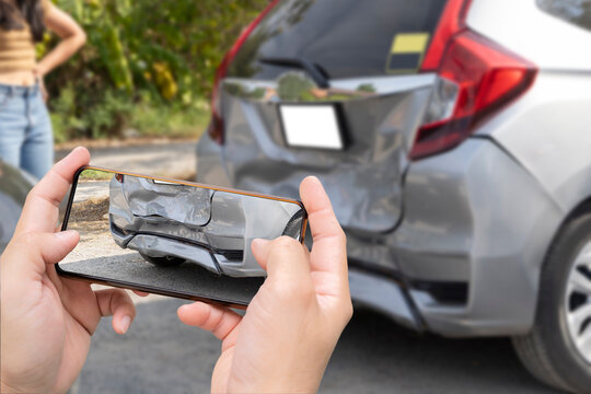 Car insurance and payout concept, damaged vehicles with a smartphone as a proof of insurance claim.