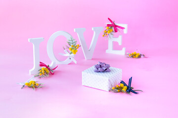 LOVEのアルファベットの文字と小さなミモザの花束とプレゼント-----バレンタイン・イメージ