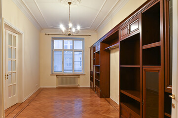 An empty room with a large window, rent, sale and furniture made of natural wood.