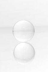 Glass ball on a mirrored surface and white background.