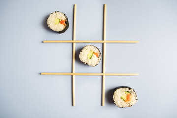 Game tic-tac-toe with chopsticks for food and sushi.