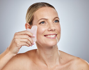 Face, beauty skincare and woman with crystal isolated on a gray studio background. Thinking, health and female model with rose quartz stone or guasha product for anti aging, massage and healthy skin.