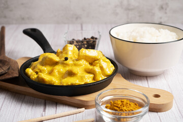 Chicken in curry sauce with boiled rice on a light background
