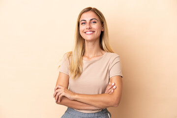 Blonde Uruguayan girl isolated on beige background keeping the arms crossed in frontal position