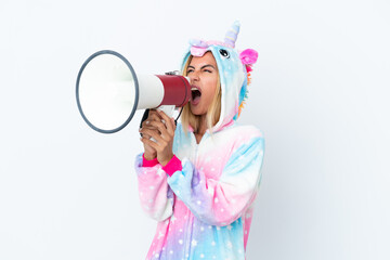 Blonde Uruguayan girl wearing a unicorn pajama isolated on white background shouting through a...