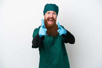 Surgeon redhead man in green uniform isolated on white background pointing to the front and smiling