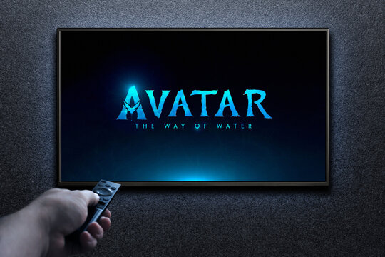 Man turns on TV with remote control. TV screen playing Avatar the way of water trailer or movie. Moscow, Russia - December 14, 2022.