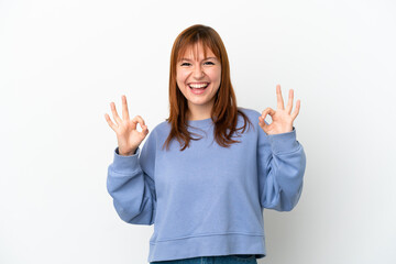 Redhead girl isolated on white background showing ok sign with two hands