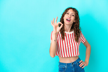 Young woman with curly hair isolated on blue background showing ok sign with fingers