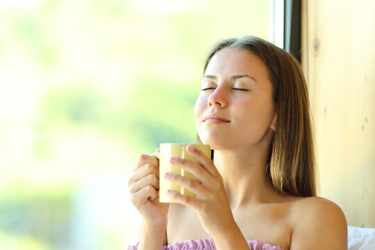 Relaxed teen smelling coffee at home