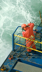Seafarer working on a deck of a container vessel with a water jet machine. Able-bodied seamen on...