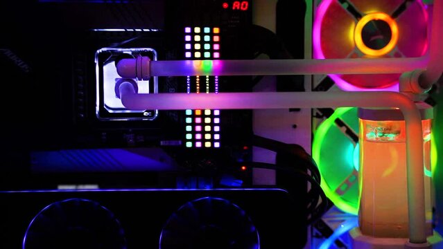 macro slow motion shot of overclocked CPU computer cabinet with water liquid cooled processors and RGB red green blue lighting with metal pipes running