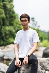 Fototapeta premium An Asian Man With White Shirt Posing Near a River in the Nature