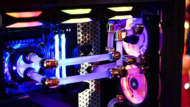 macro slow motion shot of overclocked CPU computer cabinet with water liquid cooled processors and RGB red green blue lighting with metal pipes running