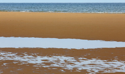 golden beach by the sea and puddles after high tide