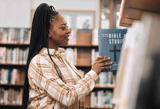 Religion book, education and black woman in a library for research, studying God and knowledge on the bible at college. Learning, smile and African student with decision of books on a scholarship