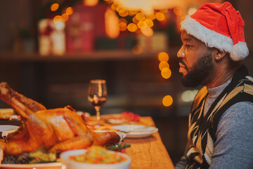 happy family Christmas dinner party African American man sitting at Christmas festive table celebrating winter holiday with family enjoying in Thanksgiving dinner party at dining table.