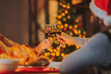 Glasses of champagne and wine in hands of people at party. happy friends or family having christmas dinner at home.