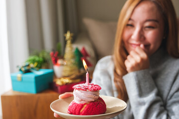 A surprised young woman receiving and holding birthday cake with candle, Christmas holiday...
