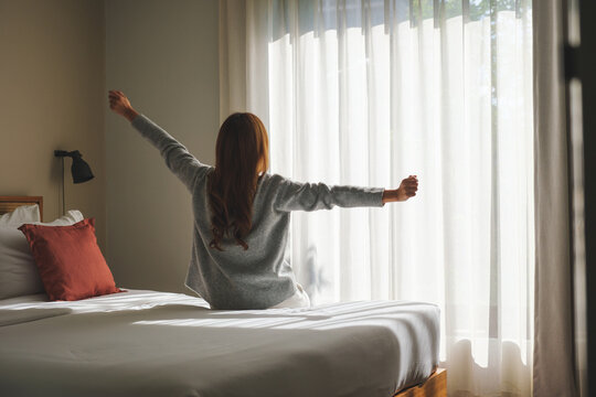 Rear view image of a woman do stretching after waking up in bedroom