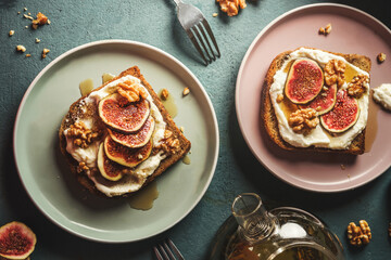 Breakfast french toasts with cream fresh, fig slices and nuts, drenched in maple syrup on plates , top view