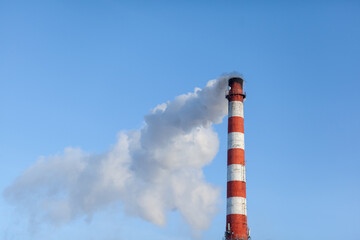 White thick smoke from the boiler room chimney. Smoke against the blue sky. Air pollution. Heating of the city. Industrial zone.