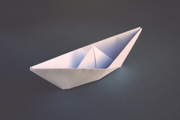 White paper boat origami isolated on a grey background
