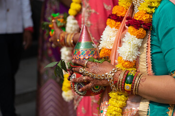 Hands of an Indian hindu woman holding sacred pot kalash during a marriage. Phere, bidai, haldi, mehendi, baraat, festival, ritual, marwari, rajputi, rajasthani, gujarati, home, house warming, vastu