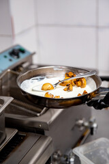 chef hand cooking sauce with mushroom sliced in pan at a restaurant kitchen