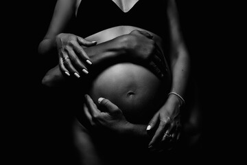 Male and female hands hug the belly of a pregnant woman. Black and white shooting.