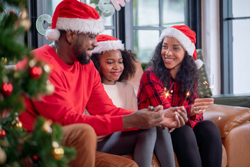 Christmas Celebration. Happy family mother, father and daughter celebrate Christmas and new year with sparklers celebrating Christmas at home.