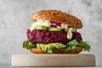 Vegan burger with beetroot cutlet, avocado and vegan mayo sauce on gray background. Healthy veggie...