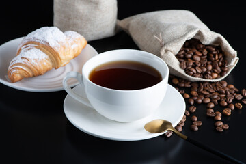 A white cup of coffee and croissant