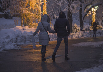 Young couple walking on snow at the Kalemegdan park in Belgrade.  View from the back. Winter scene at night.