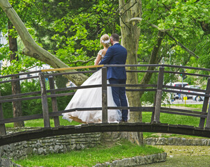 A young married couple poses on a wooden bridge