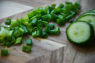 green fresh sliced onions with green sliced cucumber on a wooden board