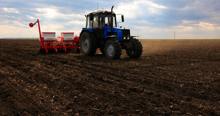 Fototapeta premium Agriculture. Tractor, Seeding Machine Working in Field on a Farm. Seeder, Planter Combine. Tillage, Plowing. Agricultural Equipment. Season Sowing Grain. Spring time Process Planting Seeds. 