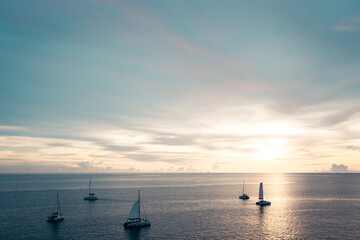 Fototapeta na wymiar Golden sunset shine over the sea with sailboats