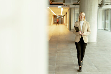 Businesswoman with digital tablet on modern office hallway